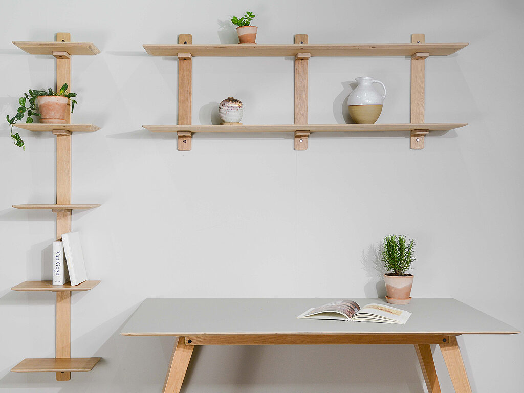 Home office set up demonstrating the Brenin desk with mushroom lino top, various artist books, plant pots and earthenware pottery resting on Avon open wall shelving storage units