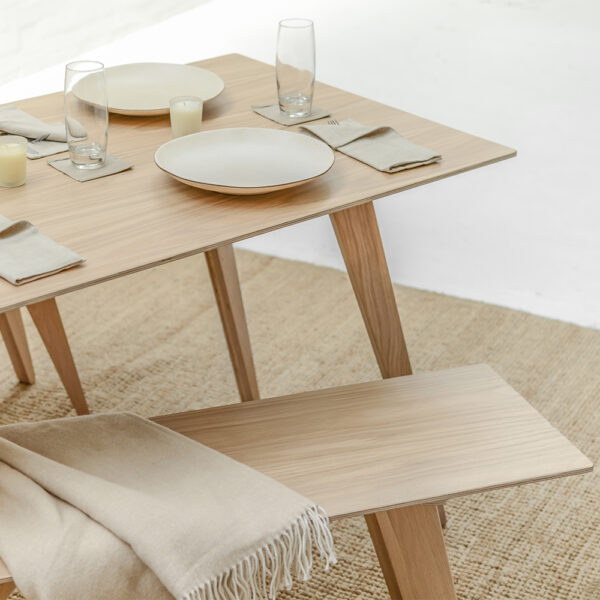 An Oak veneered Brenin Bench Seat is pulled away from an elegant matching Brenin Dining Table